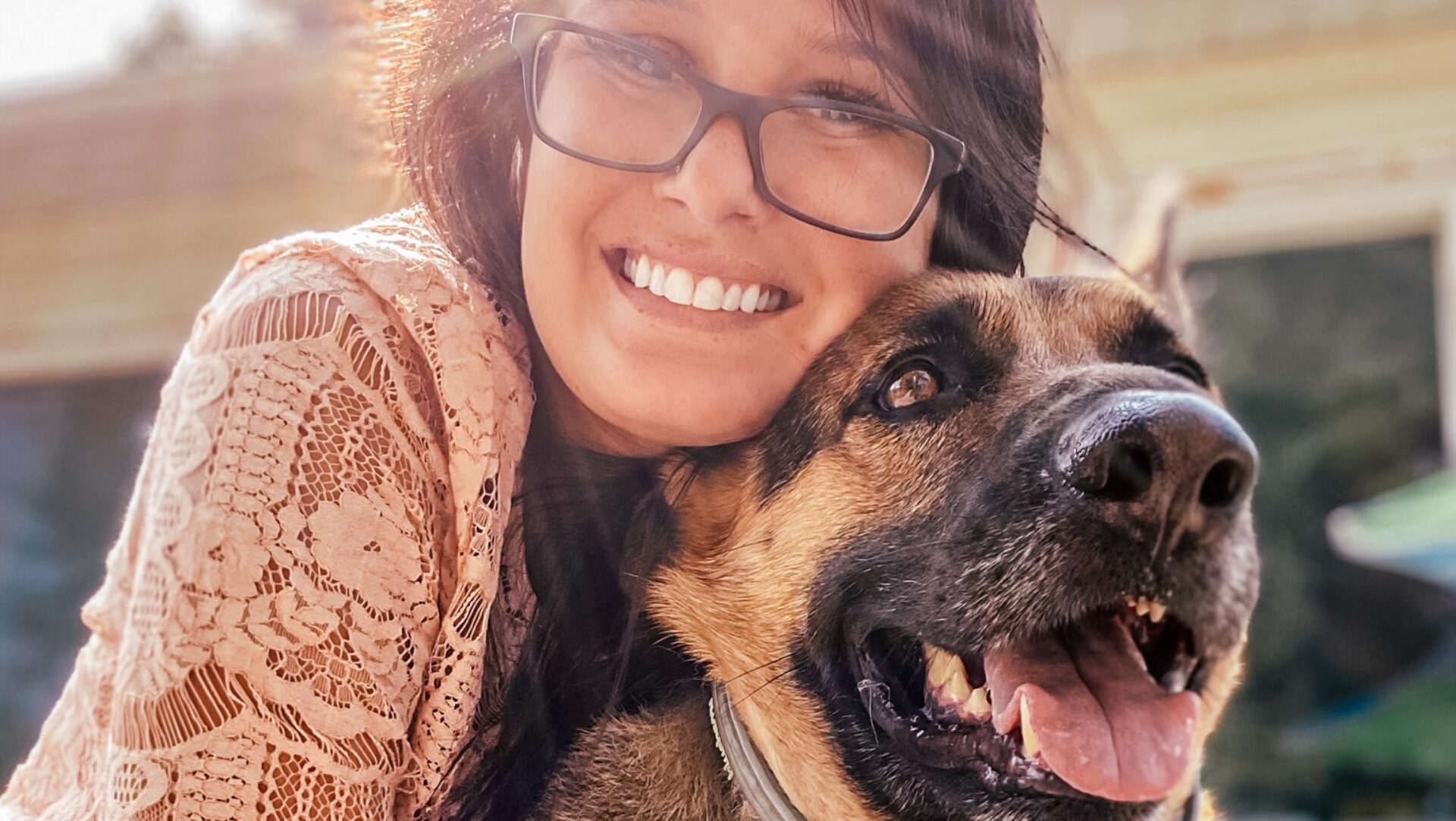 a lady wearing glasses is hugging a dog